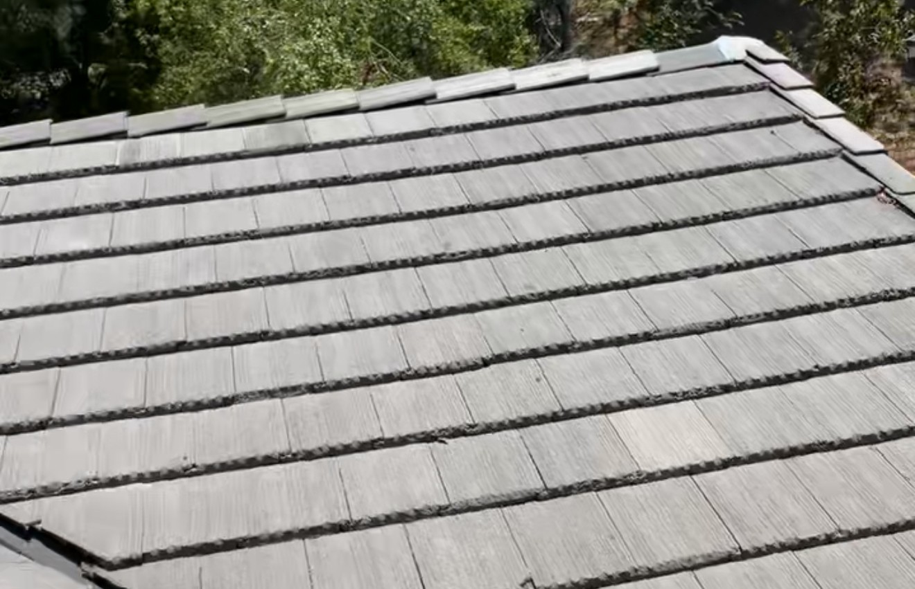 Close view of flat gray roof tiles laid in even rows up a sloped roof.