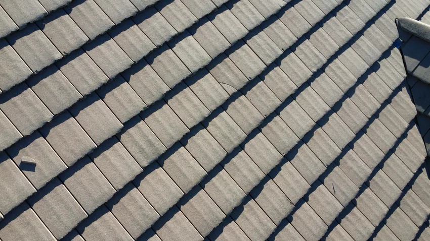 Close-up of gray flat roof tiles laid in rows, with a broken tile fragment lying on the surface