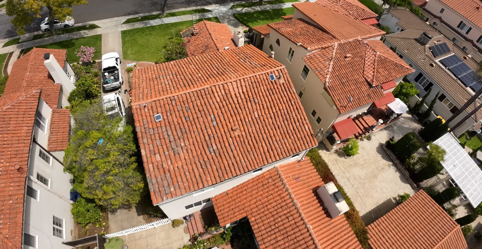 Aerial view of neighboring houses with clay barrel tile roofs, driveways and a parked work van